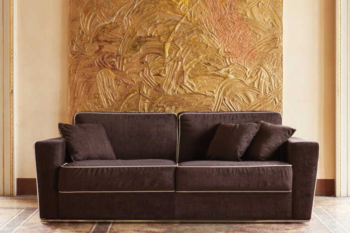 Retrohs Sofa lässt sich in ein Bett verwandeln. Die Kontrastbordüre heben die Form der Armlehnen, die im Unterteil dünner werden. 